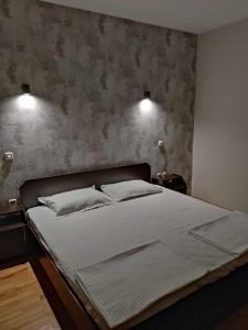 a bed in a bedroom with two lights on the wall at Apartments Philip II in Ohrid