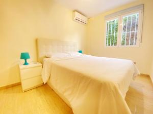 a bedroom with a white bed and a window at Jardines de Banús Apartments in Marbella