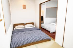 een kleine slaapkamer met een bed en een spiegel bij Panda Stay Okayama in Okayama