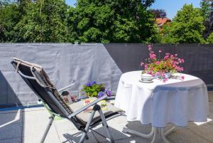 a table and a chair with flowers on a patio at Penthaus Kranichholz in Lüdinghausen