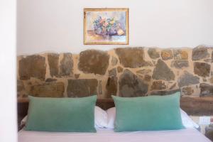 1 cama con 2 almohadas verdes frente a una pared de piedra en Podere Belvedere Tuscany, en Pontassieve