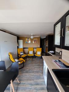 ein Wohnzimmer mit gelben Stühlen und eine Küche in der Unterkunft Appartement avec parking Cap d'Agde, La Falaise in Cap d'Agde