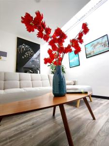 ボゴタにある8 Apartaestudio Cedritos independienteのリビングルームのテーブルの上に置かれた赤い花の入った花瓶 +1枚の写真