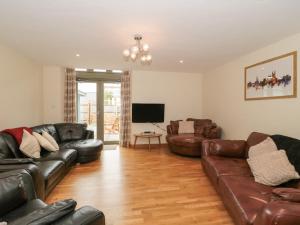 a living room with leather furniture and a flat screen tv at The Old Schoolrooms in Radstock