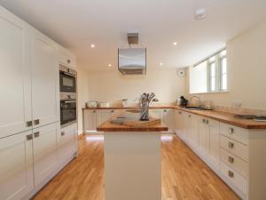 a kitchen with white cabinets and a wooden floor at The Old Schoolrooms in Radstock