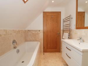 a bathroom with a bath tub and a sink and a mirror at The Old Schoolrooms in Radstock +35 photos