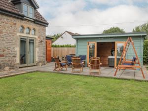 eine Terrasse mit Stühlen und einer Spielstruktur im Hof in der Unterkunft The Old Schoolrooms in Radstock