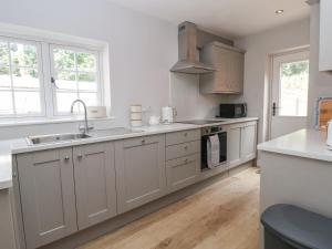a kitchen with white cabinets and a sink at 1 Golf Links Cottages in Northwich
