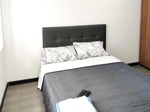 ein Schlafzimmer mit einem Bett mit zwei Fernbedienung in der Unterkunft 8 Apartaestudio Cedritos independiente in Bogotá