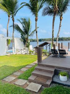 a deck with two chairs and palm trees at Villa Assinie Bord de Lagune in Assinie