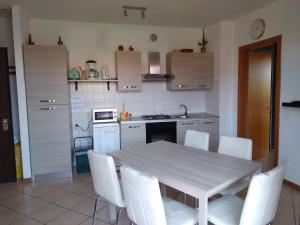 cocina con mesa blanca y sillas blancas en Flat Garda, en Cavalcaselle