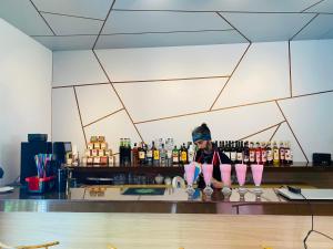 a woman standing behind a bar with four pink glasses at Ef Palace Shekvetili in Shekhvetili