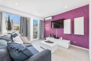 a living room with a purple accent wall at Coração do Mar by OCvillas in Albufeira
