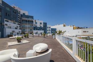 a balcony with white chairs and tables and buildings at Coração do Mar by OCvillas in Albufeira