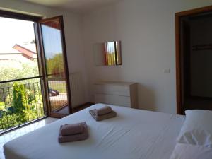 1 dormitorio con 1 cama blanca y 2 toallas en Flat Garda, en Cavalcaselle