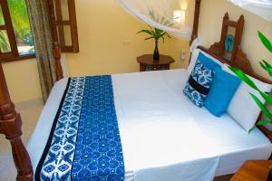 a bedroom with a bed with blue and white pillows at Baharini beach cottage in Malindi