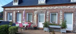 a brick house with a table and chairs on a patio at Le Jardin des Poules in Thiétreville