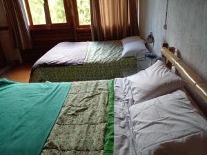 two twin beds sitting in a room with windows at La Casita de Oxapampa in Oxapampa