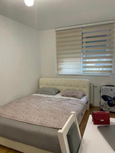 a bedroom with a bed and a window and a desk at Sarajevo Otoka - Stan na dan in Sarajevo