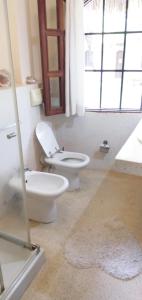 a bathroom with a toilet and a sink and a window at Baharini beach cottage in Malindi +55 photos