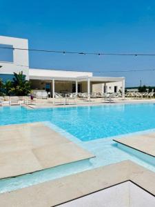 a large swimming pool with chairs and a building at Hotel Belsito in San Pietro in Bevagna