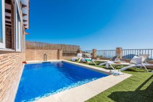 einen Pool mit zwei Stühlen neben einem Haus in der Unterkunft Cortijo Las Vistas in Cómpeta