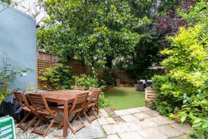 倫敦的住宿－GuestReady - A charming stay in Highgate，花园里的一张木桌和椅子