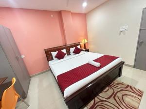 a bedroom with a bed with red and white sheets at Hotel Prime Classic in Shamshabad