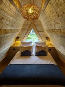 uma cama num quarto de madeira com uma grande janela em Au Coin du Bois em Langolen