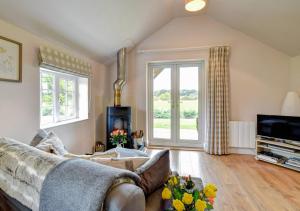 a living room with a couch and a tv at Tui Cottage in Snape