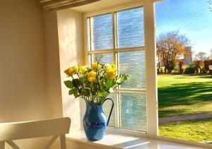 a vase of yellow flowers sitting in a window at Tui Cottage in Snape