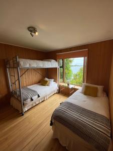 1 dormitorio con 2 literas y ventana en Cabañas Bahia Celeste, Puerto Varas, en Puerto Varas
