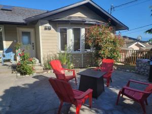 four red chairs and a table in front of a house at Eagle's View Penthouse in Victoria