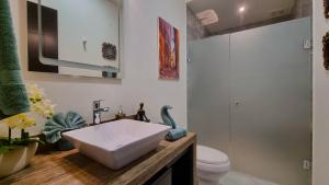a bathroom with a white sink and a toilet at Palacio Huatulco - 2D in Santa Maria Huatulco +6 photos