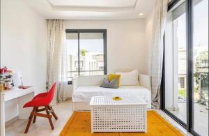 um quarto branco com uma cama e uma cadeira vermelha em Villa Eden luxe em Bouskoura