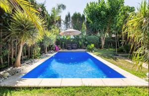 a swimming pool in a backyard with palm trees at Villa Eden luxe in Bouskoura