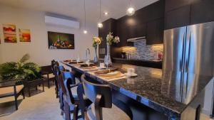 a large kitchen with a long bar with blue chairs at Palacio Huatulco - 2D in Santa Maria Huatulco