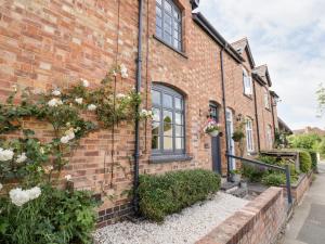 una casa de ladrillo con flores a un lado. en Ross Cottage, en Evesham