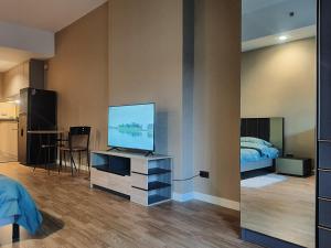 a bedroom with a television on a dresser with a bed at Baan Nonzee Condo in Bangkok