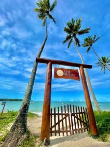 a sign on a beach with palm trees at Flat Eco Resort Praia Dos Carneiros in Praia dos Carneiros