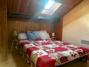 a bedroom with a bed with a red and white blanket at Joli appartement dans une maison ancienne in Ax-les-Thermes