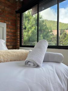 a towel sitting on top of a bed with a window at OPE Suites Usaquen in Bogotá