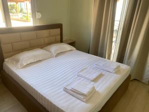 1 cama con 2 toallas y ventana en Blue Breeze Attic Apartments, en Sarandë