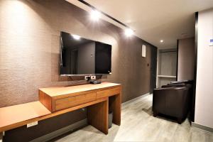 una camera con scrivania e TV appesa a un muro di Golden Home Hotel a Taipei