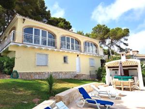 a large yellow house with chairs and a patio at Holiday Home Maria in Jávea