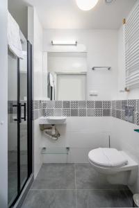 a white bathroom with a toilet and a sink at JESS INN Hostel Rondo Charles de Gaulle in Warsaw