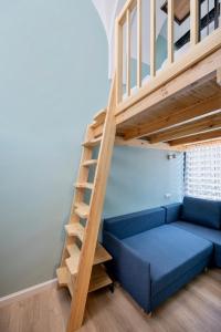salon z niebieską kanapą i drewnianymi schodami w obiekcie JESS INN Hostel Rondo Charles de Gaulle w Warszawie