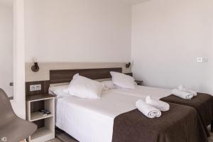 a bedroom with two beds with white pillows and a chair at Mesón Hostal La Cabaña in Medellín