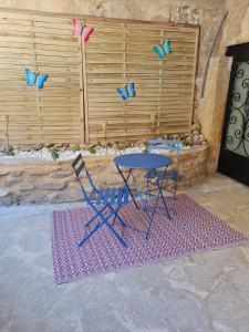 a table and a chair and butterflies on a fence at Chez Karine - Appartement in Lédenon