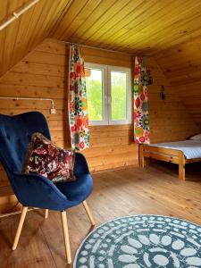 um quarto com uma cadeira, uma cama e uma janela em Domki letniskowe Stary dąb em Solina
